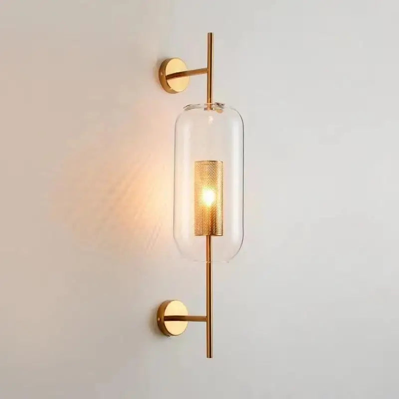 Modern gold-toned brass glass wall lamp with a clear cylindrical shade and perforated center for bedroom decorbites brass glass sconce
