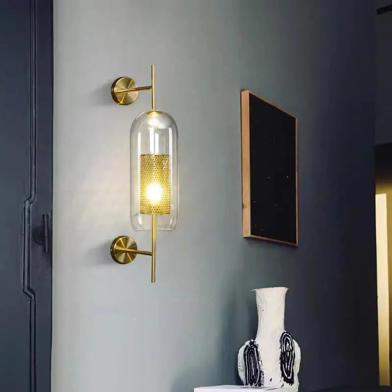 Modern brass glass wall lamp with perforated gold sconce and clear glass cylinder for elegant bedroom decorbites brass glass