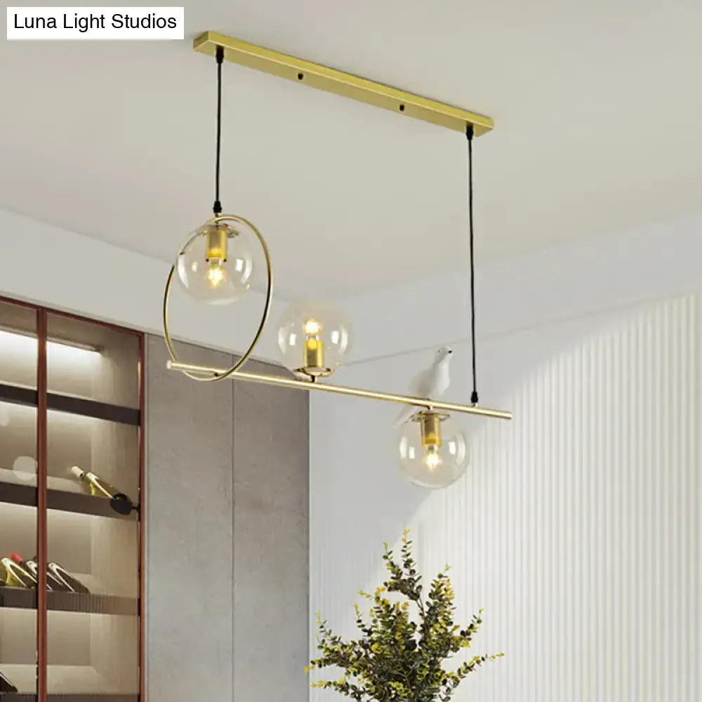 Modern brass global island lamp with gold-toned pendant light and clear glass globes suspended by black cords