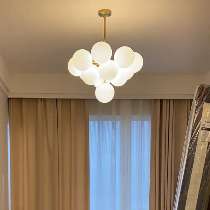 Modern brass globe pendant lamp with gold finish and multiple frosted glass spheres clustered for dining room