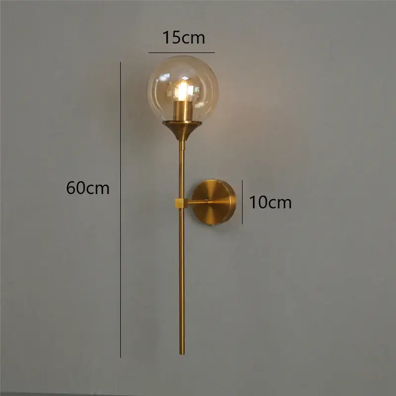 Modern brass golden glass ball wall lamps with a gold-toned metal stem and clear globe for elegant bedroom lighting decorbites golden glass