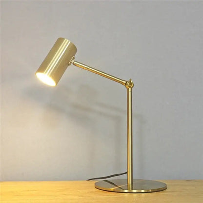 Modern brass golden table lamp with gold finish adjustable cylindrical head and slender articulated arm for reading desk light