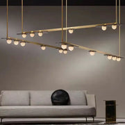 Modern brass pendant light fixture with multiple spherical gray glass led bulbs in intersecting horizontal bars