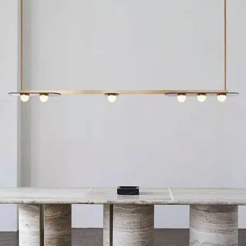 Modern brass gray glass led chandeliers featuring six warm bulbs suspended above a marble dining table