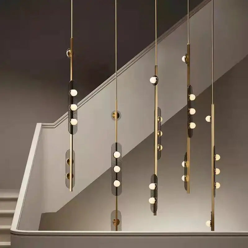 Modern brass gray glass led chandeliers with gold-toned pendant lights and sleek vertical rods above a staircase