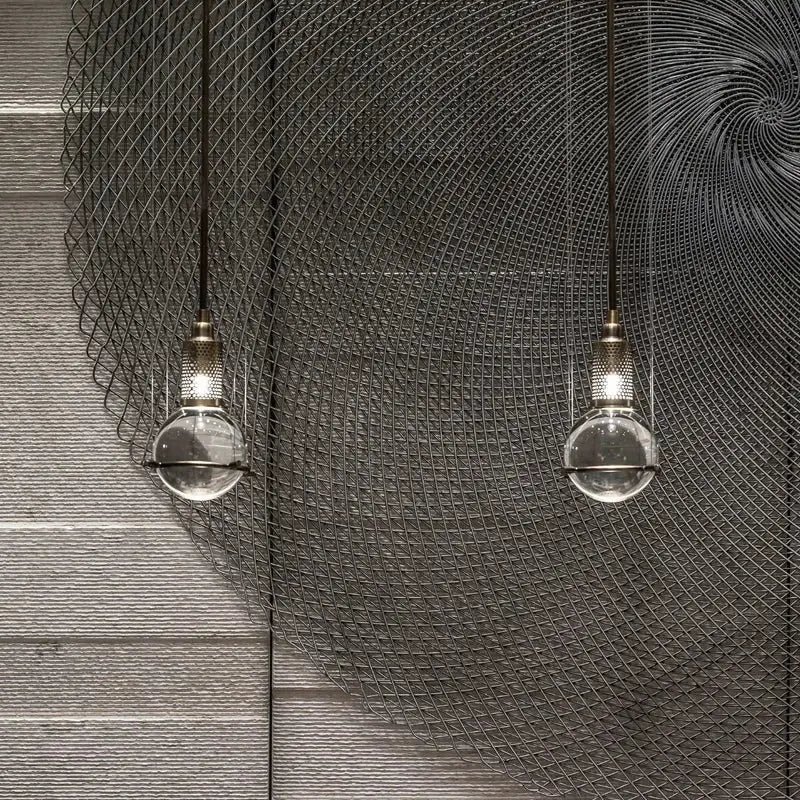 Two clear glass globe pendant lights with brass fixtures hang against a dark wire mesh backdrop decorbites crystal ball led