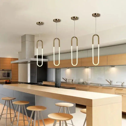 Four modern pendant lights with curved brass frames and glowing white led tubes in a modern brass led u-shaped bar chandelier