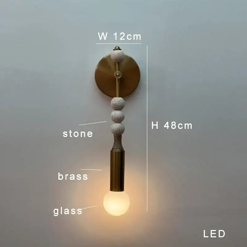 Modern brass marble ball wall sconce with a brass circular backplate, three textured stone beads, and glass bulb housing by decorbites