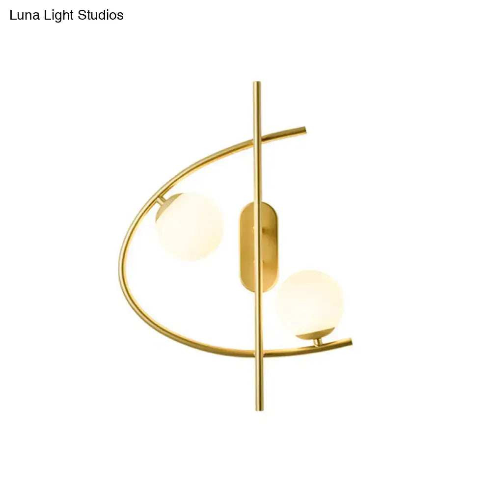 Modern brass wall sconce with gold-toned curved metal frame and two frosted milk glass ball shades for living room