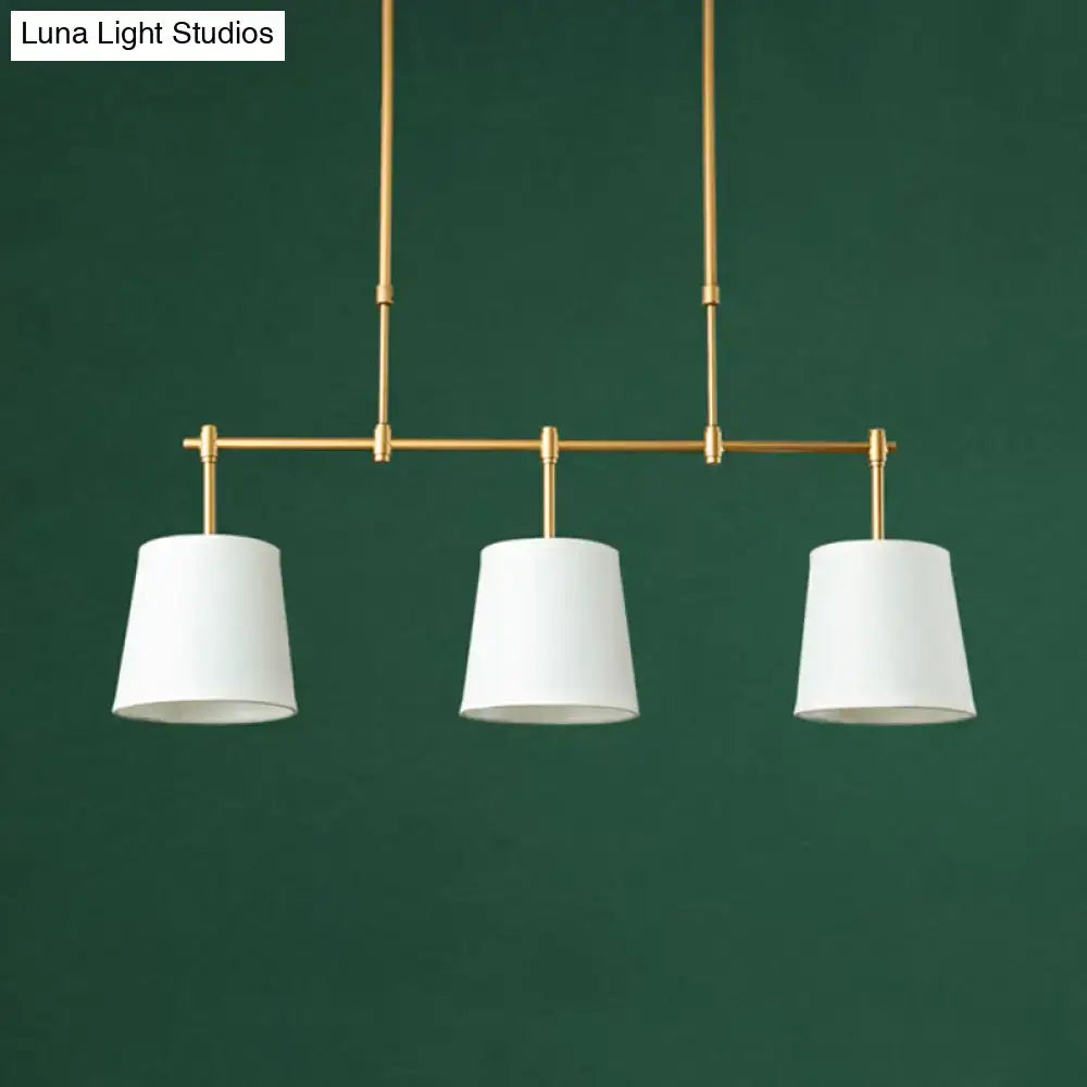 Modern brass pendant light with three white green flaxen cylindrical shades for dining room lighting