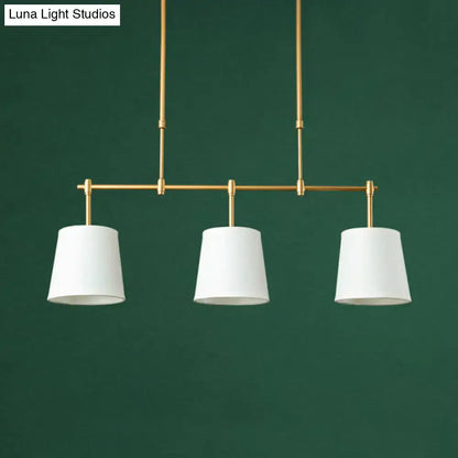 Modern brass pendant light with three white green flaxen cylindrical shades for dining room lighting