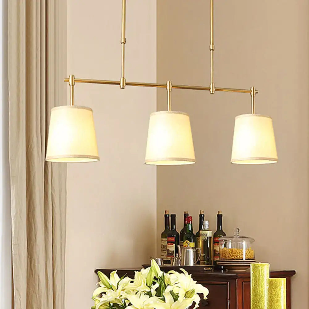 Modern brass pendant light with gold-toned bar and three white green flaxen cylindrical fabric shades for dining room