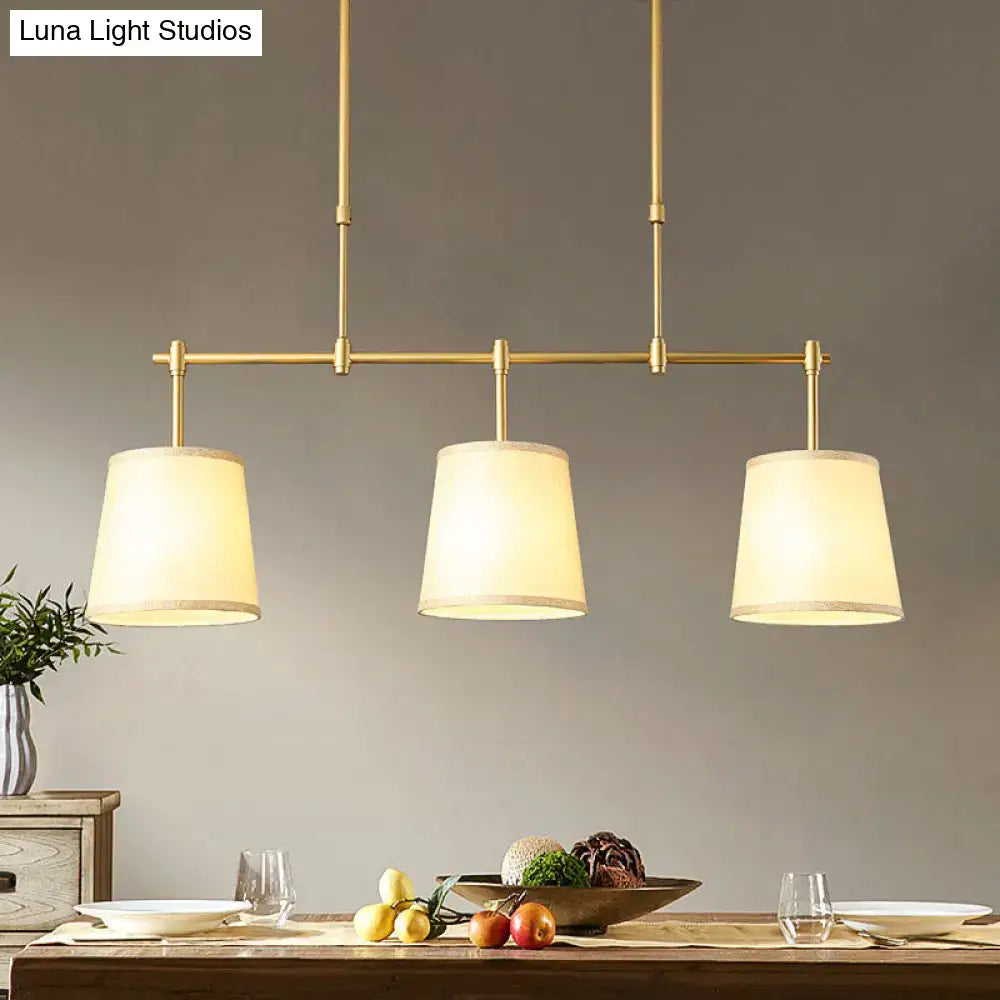 Modern brass pendant light with three cylindrical white green flaxen fabric shades for dining room lighting