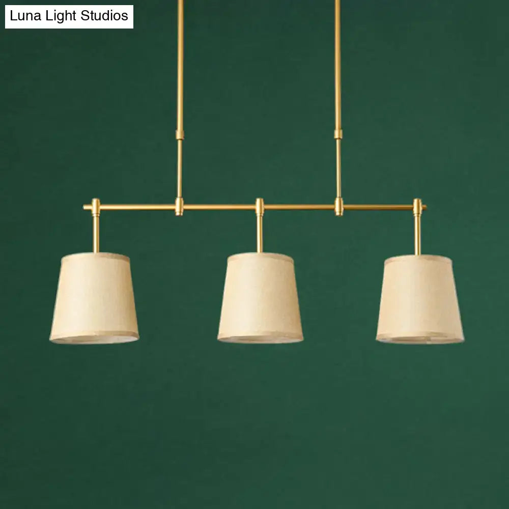 Modern brass pendant light with three off-white white green flaxen fabric shades suitable for dining room use