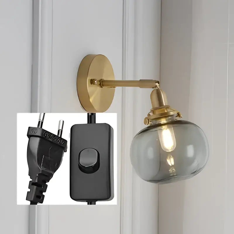 Modern brass ribbed glass ball wall sconce with a smoked glass globe and integrated black power switch by decorbites glass ball wall