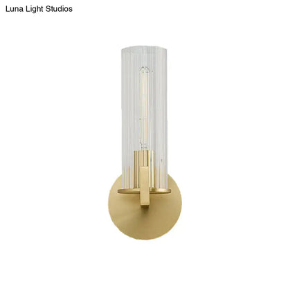 Modern brass wall sconce with a cream glass cylindrical shade and gold-toned metal base for bedroom lighting
