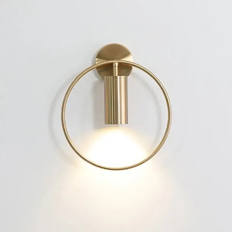 Modern brass ring led wall lamp featuring a circular brass sconce with a cylindrical led wall light fixture for bedroom use