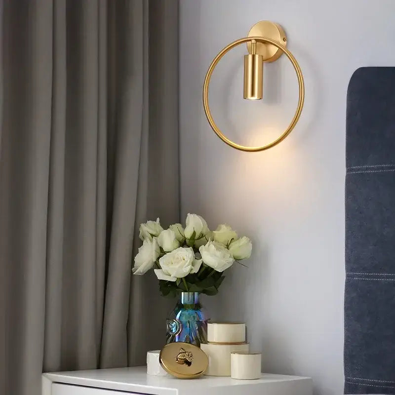 Gold-toned modern brass ring led wall lamp with cylindrical light fixture for bedroom use in a sleek design