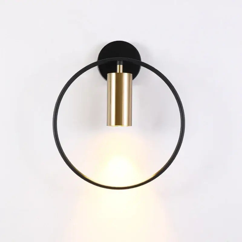 Modern brass ring led wall lamp with sleek black circular frame and polished gold cylindrical light for bedroom sconce