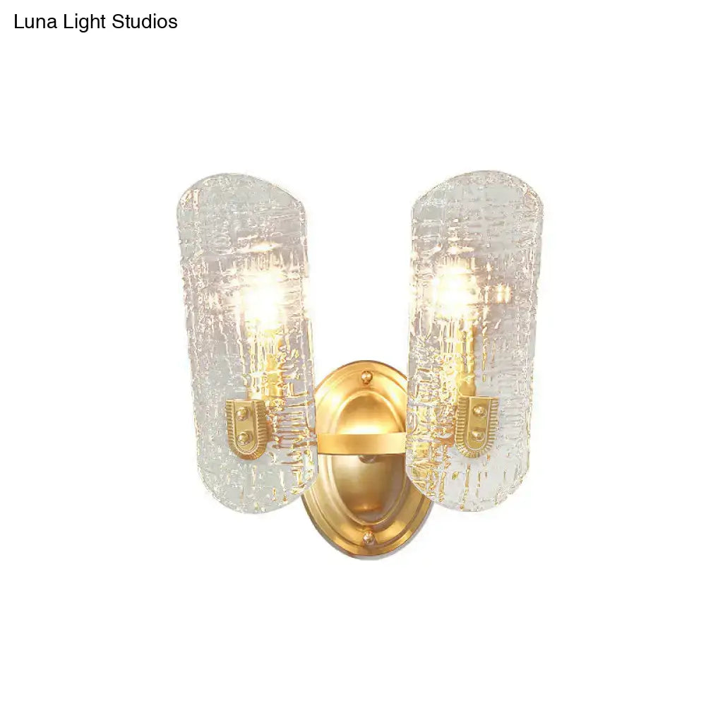 Modern brass sconce with two lights featuring gold-toned frame and clear water glass shades for living room decor