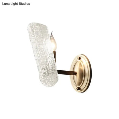 Antique brass wall sconce with two lights and textured clear water glass shade for living room use