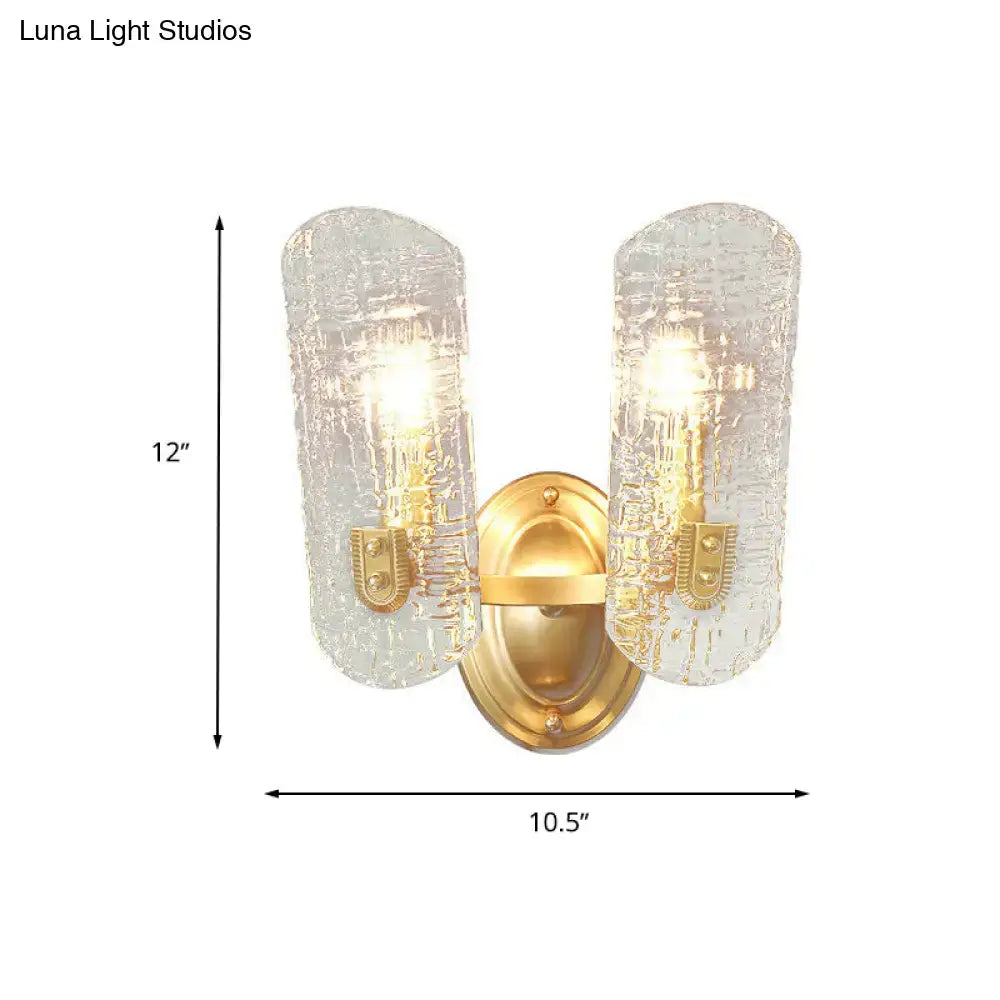 Modern brass sconce with two lights featuring gold-toned metal and clear water glass shades for living room use