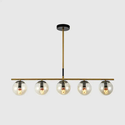 Modern brass and smoke grey globe chandelier featuring five clear glass globes with black accents for kitchen island lighting