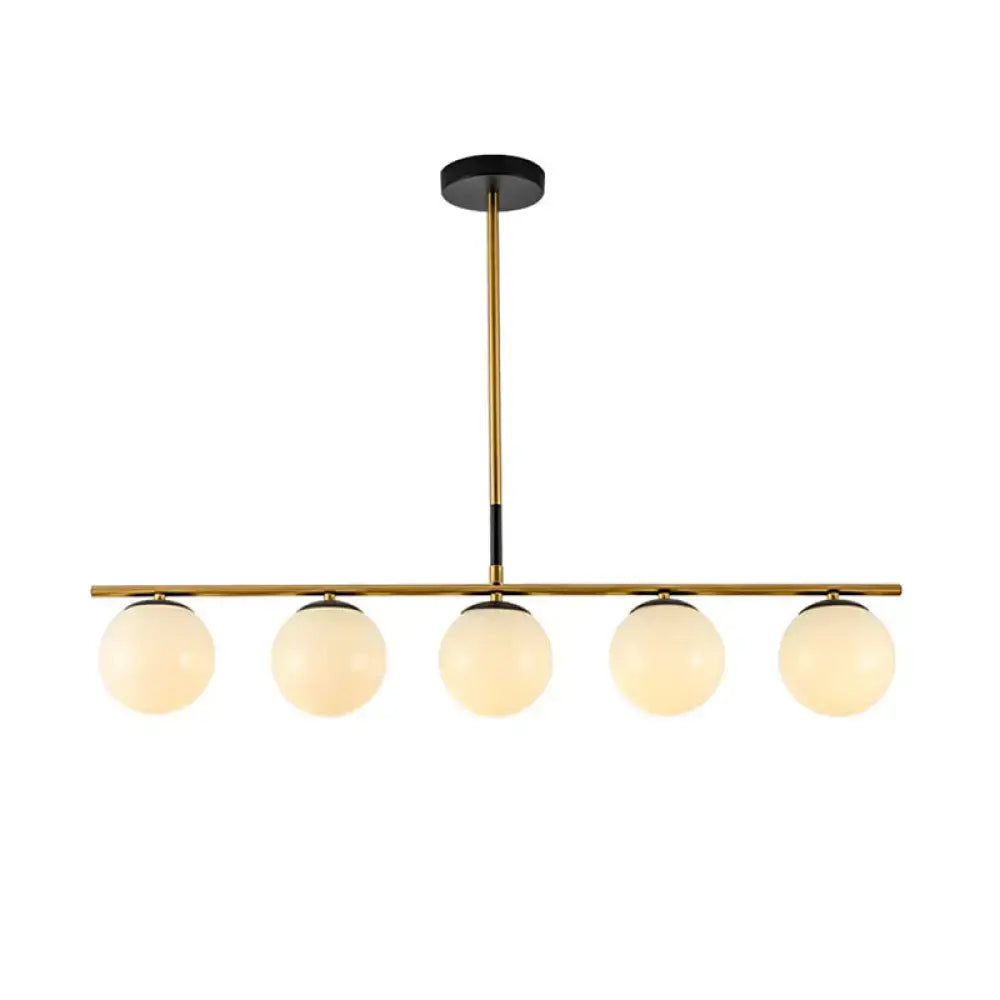 Modern brass and smoke grey globe chandelier with five frosted glass shades for kitchen island lighting