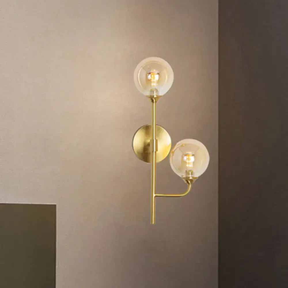 Modern brass wall sconce with two spherical glass globes in amber smoke gray for stylish bathroom lighting