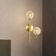 Modern brass wall sconce with two spherical glass globes in amber smoke gray for stylish bathroom lighting