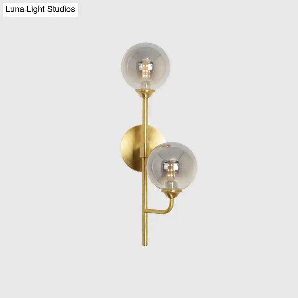 Modern brass sphere wall sconce with amber smoke gray glass shades for bathroom lighting in gold tone