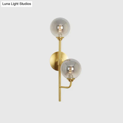 Modern brass sphere wall sconce with amber smoke gray glass shades for bathroom lighting in gold tone