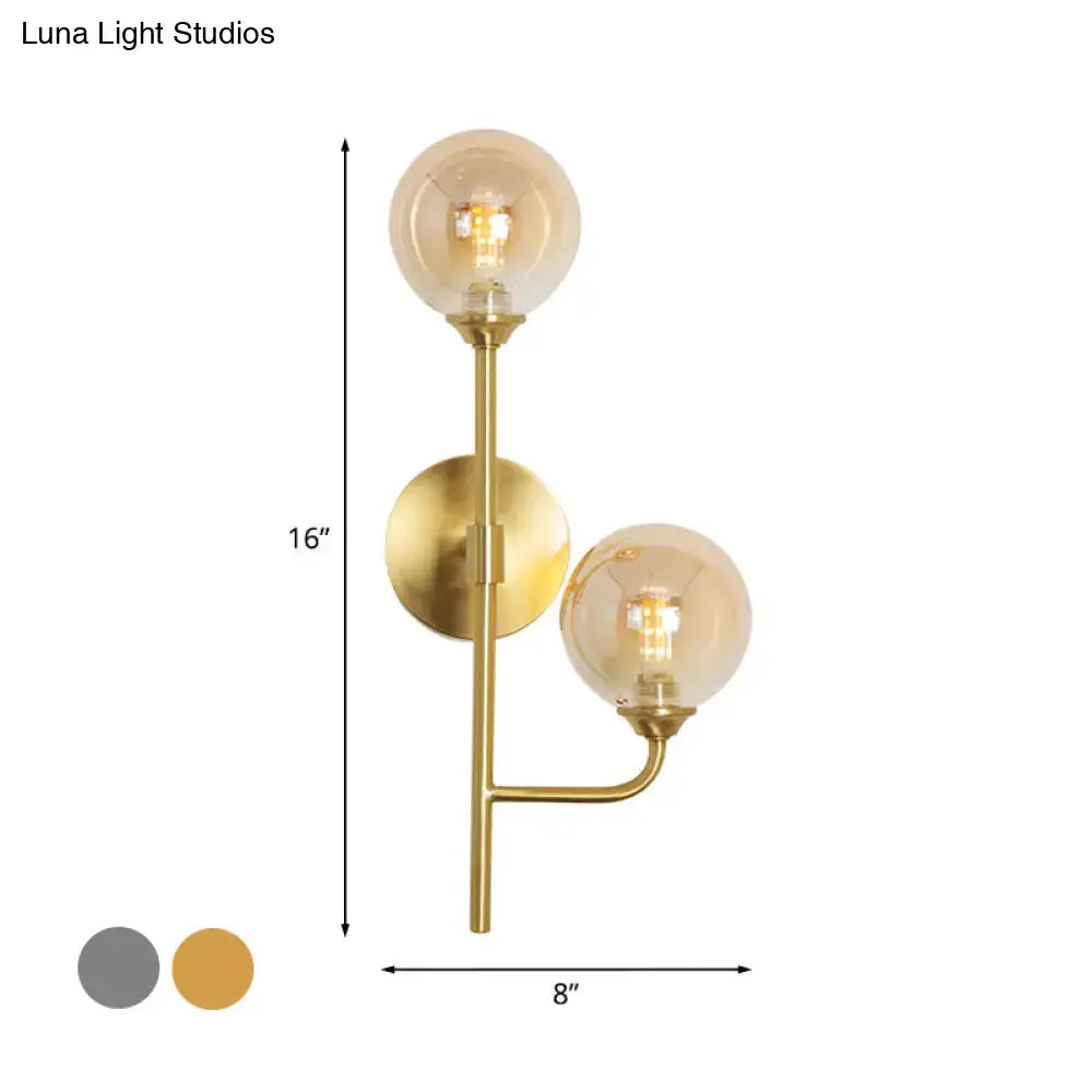 Modern brass sphere wall sconce with amber glass bulbs and smoke gray minimalist brass finish for bathroom lighting