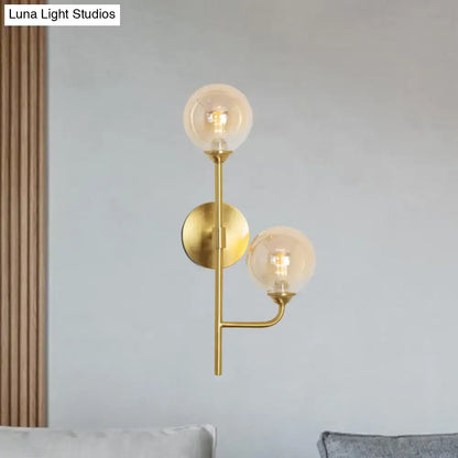 Modern brass sphere wall sconce with amber smoke gray glass globes in a gold-toned minimalist bathroom light design