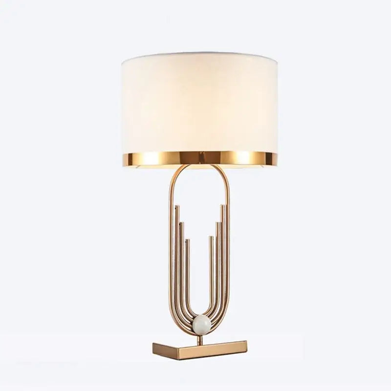Modern brass table lamp with gold paperclip design, cream fabric shade, and polished metal base from decorbites brass table collection