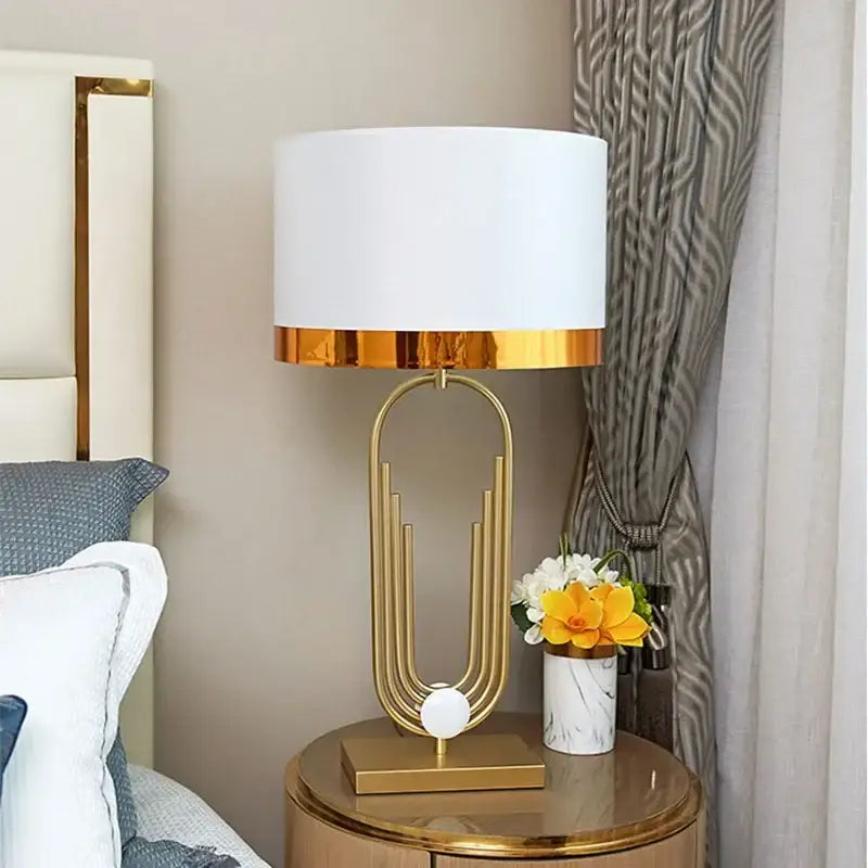 Modern brass table lamp with gold paperclip design and white shade by decorbites brass for bedroom decor