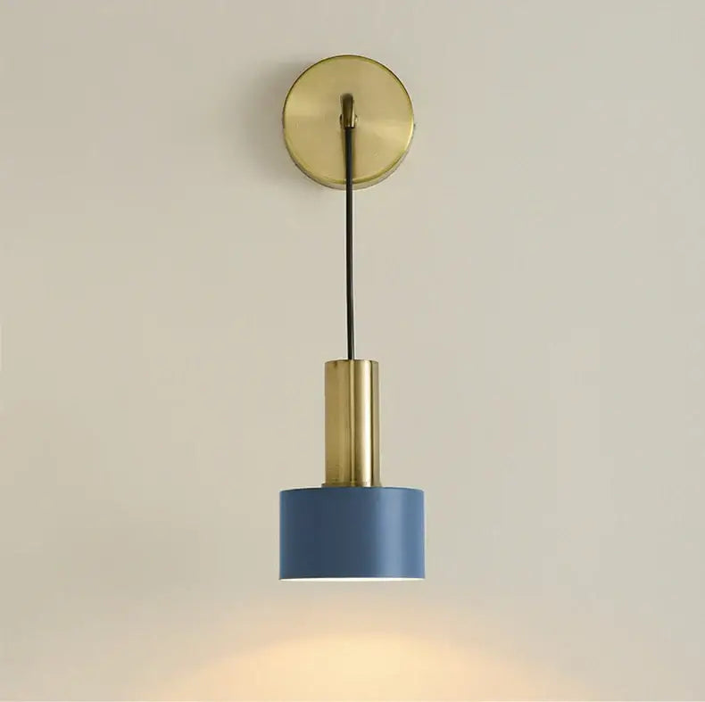 Modern brass wall lamp with a brass circular base, black cord, and blue cylindrical shade for minimalist decorbites decor