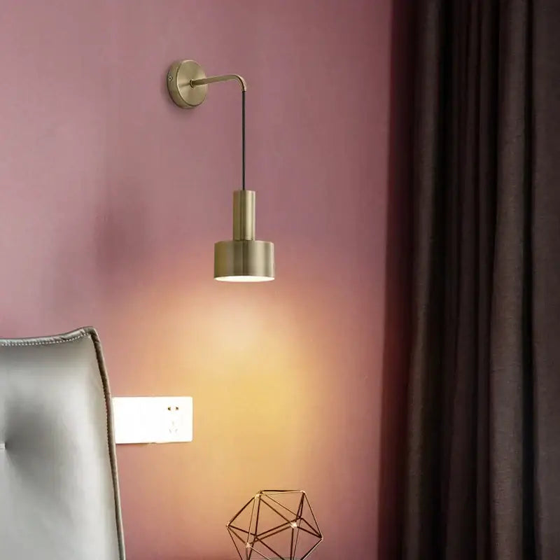 A sleek brass wall lamp with minimalist geometric design and cylindrical shade for modern living room decorbites brass wall lamp