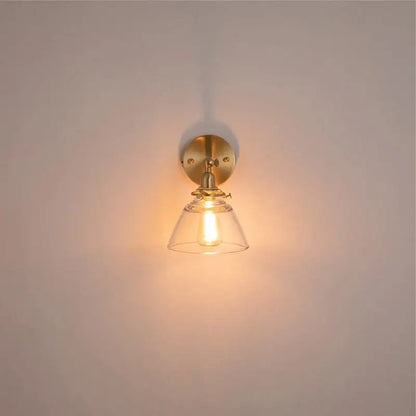 Modern brass wall lamp with warm-toned brass and clear glass bell-shaped shade for bedroom reading decorbites clear glass