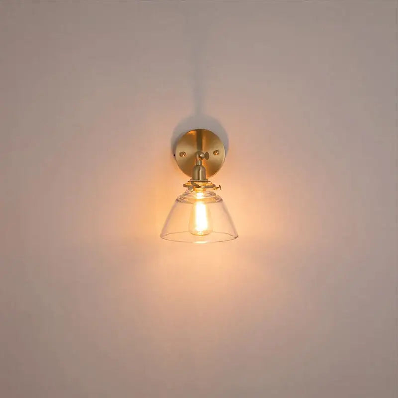 Modern brass wall lamp with warm-toned brass and clear glass bell-shaped shade for bedroom reading decorbites clear glass