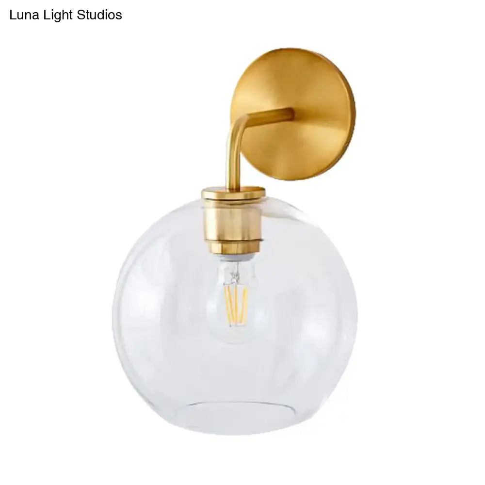 Modern brass wall lamp with clear white glass globe and exposed filament bulb for bedroom lighting