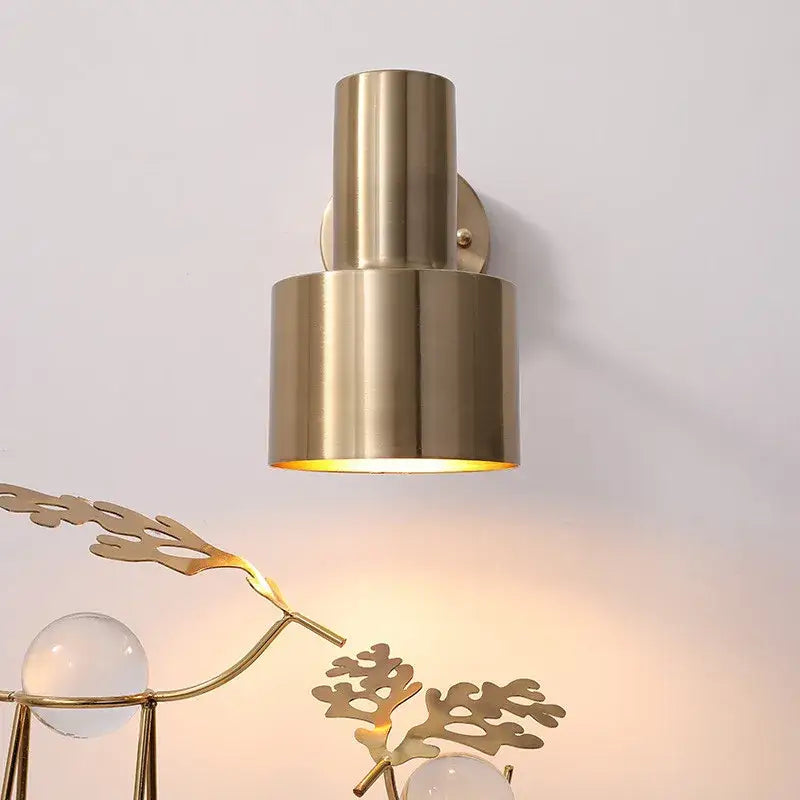 Modern brass wall lamp with pull chain switch featuring a cylindrical design and warm light from its open base