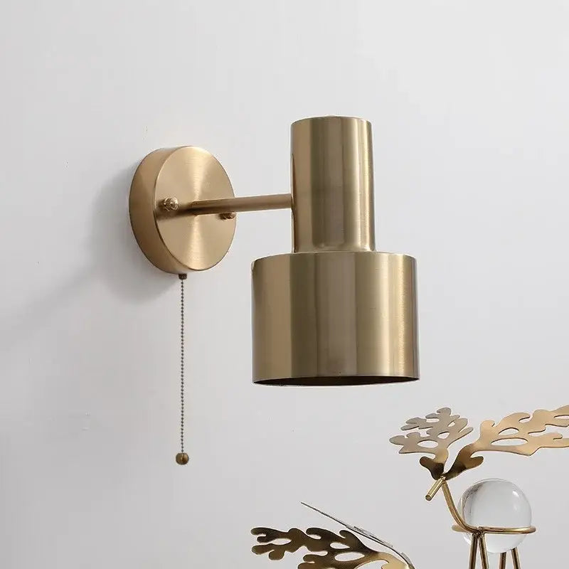 Modern brass wall lamp with pull chain switch featuring a cylindrical shade and brass finish for bedroom decor