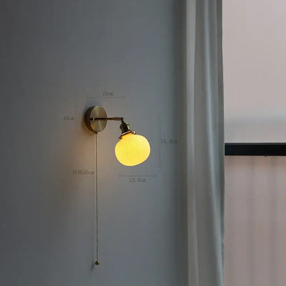 Modern brass wall lamp with warm yellow globe, ribbed glass shade, and decorbites copper arm pull-chain switch for reading light