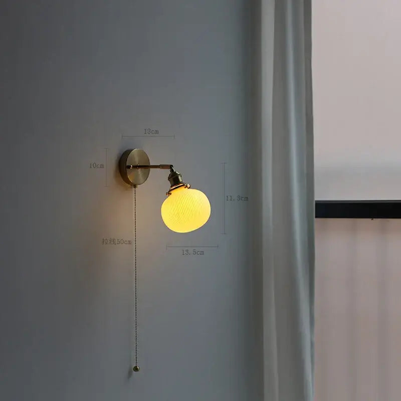 Modern brass wall lamp with warm yellow globe, ribbed glass shade, and decorbites copper arm pull-chain switch for reading light