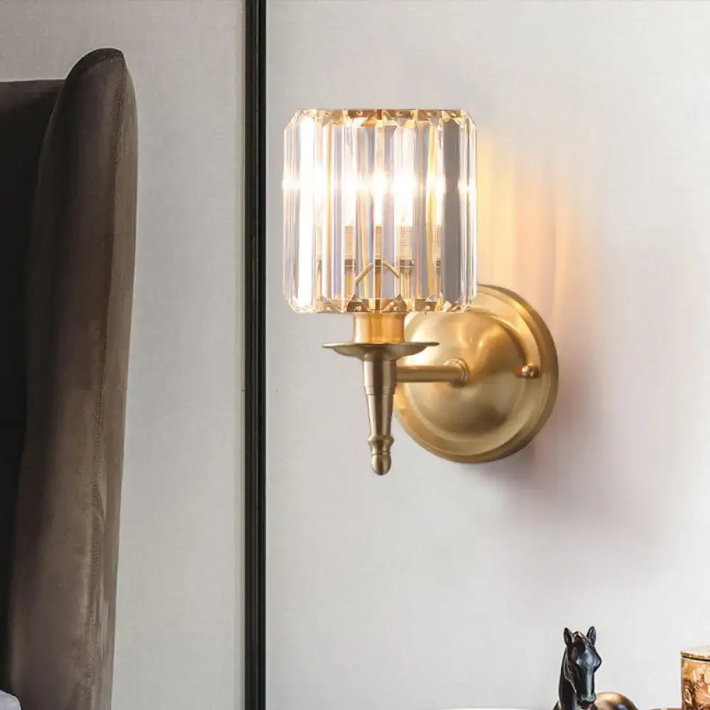Modern brass wall light sconce with gold-toned finish and faceted crystal shade for bedroom lighting