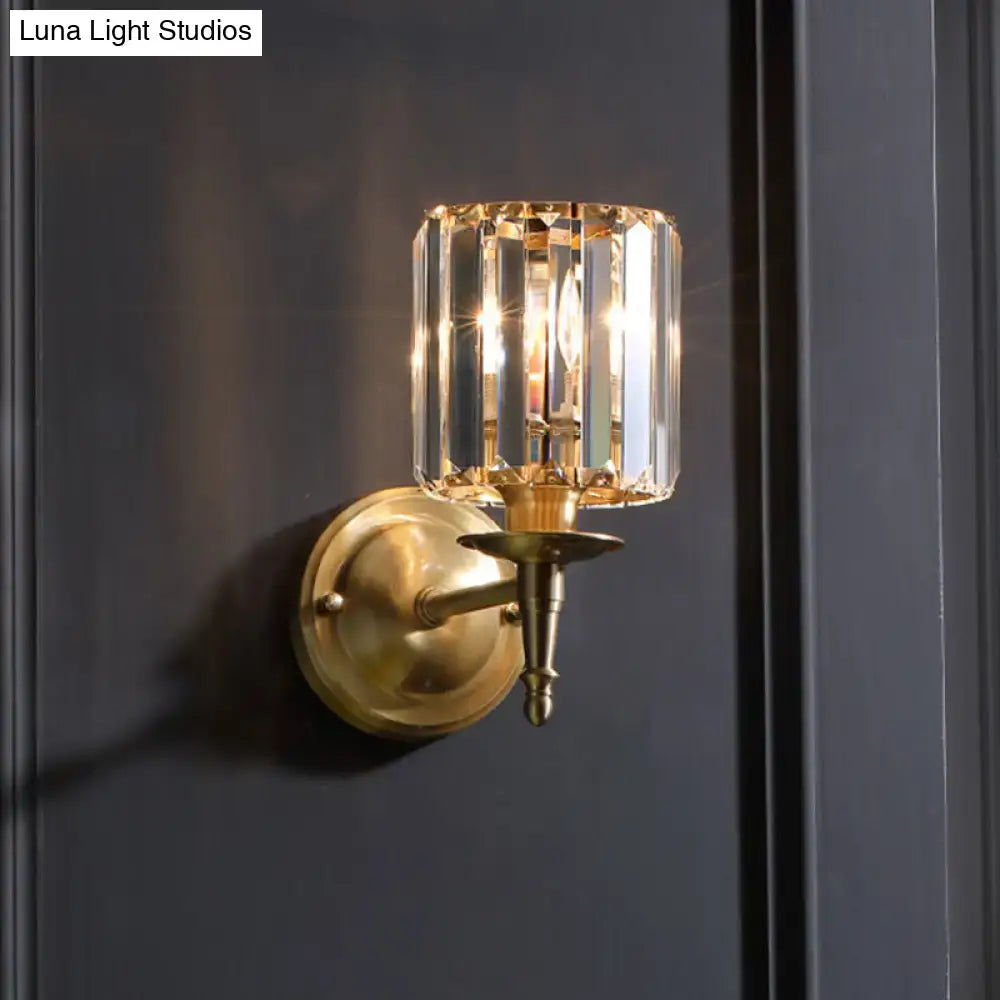 Modern brass wall light sconce with cylindrical crystal shade refracting light for elegant bedroom lighting
