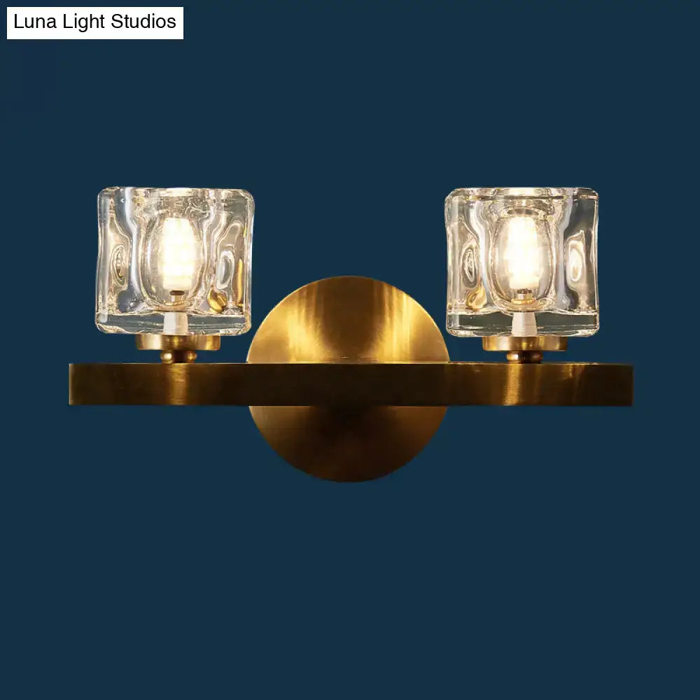 Modern brass wall light with clear crystal block and two clear textured glass shades for living room use