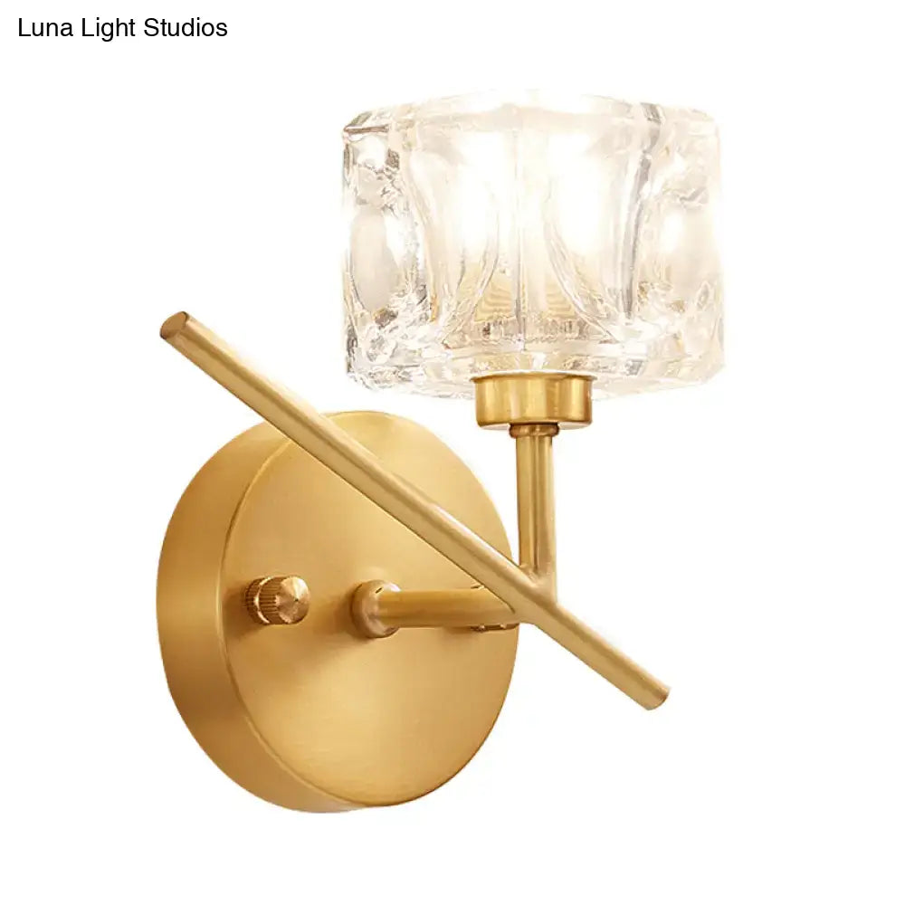 Modern brass wall light with gold-toned finish and clear crystal shade designed as a bedroom sconce with faceted glass