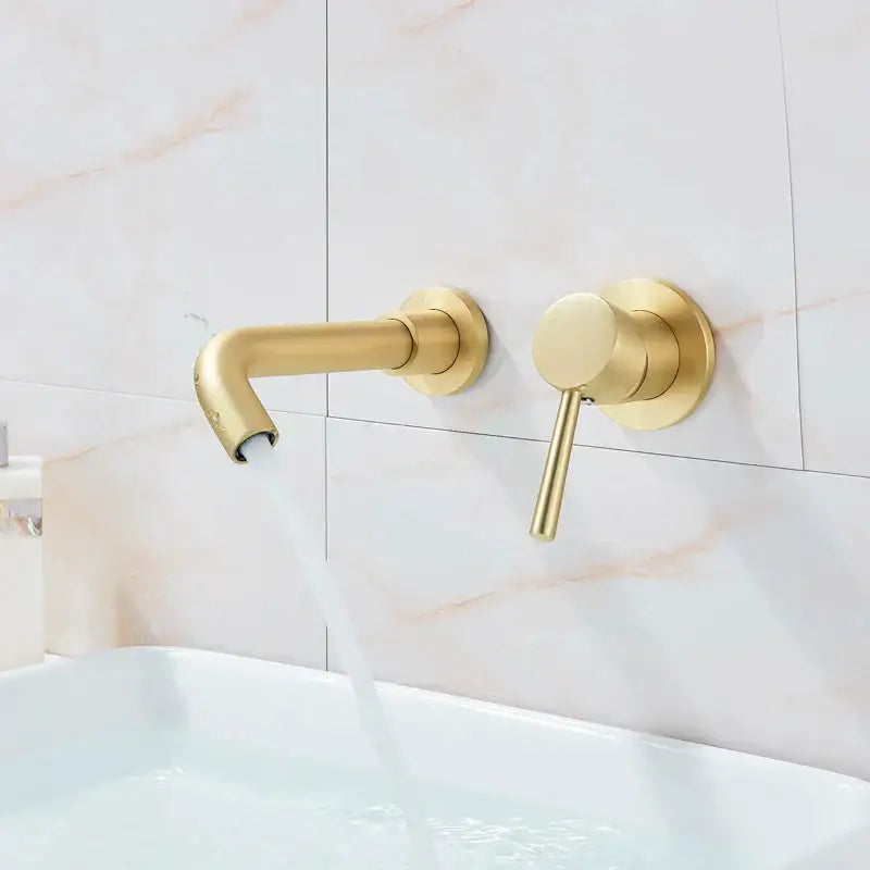 Modern brass wall mount basin faucet with gold-toned curved spout and matching cylindrical handle for bathroom use